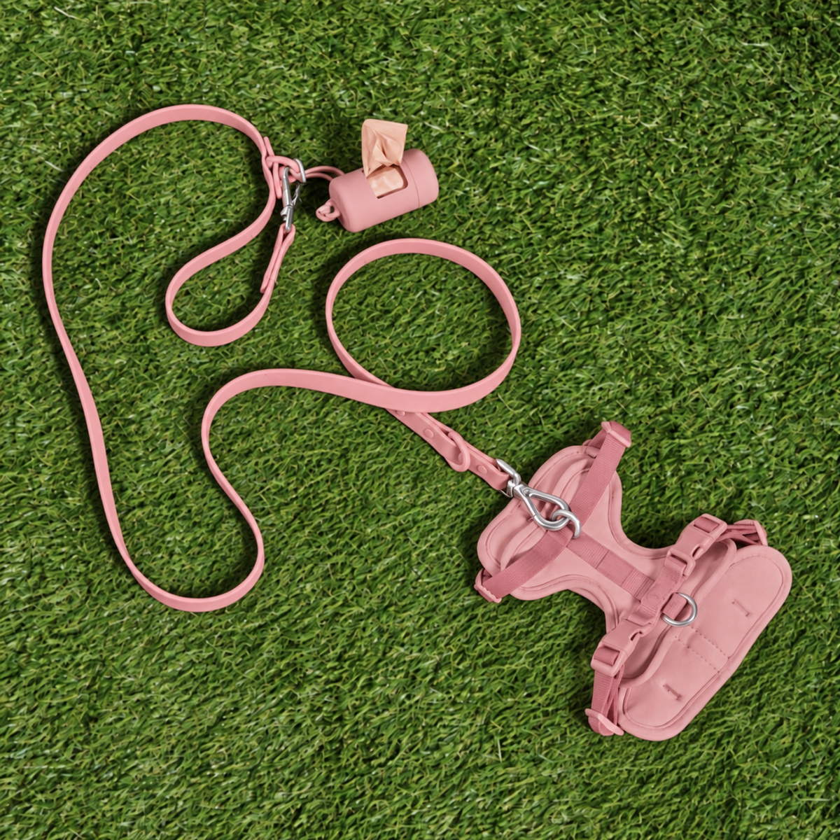 Pink dog walking kit with harness, leash, collar and poop bag dispenser on grass